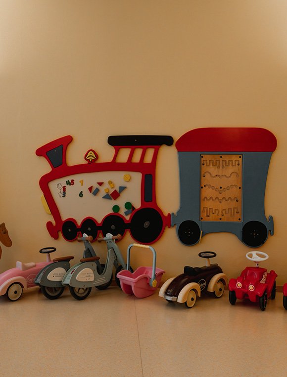 Wand mit Spielzeugzug und Rutschfahrzeugen für Kinder