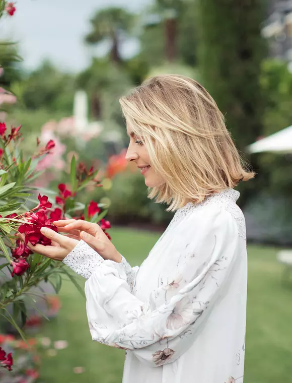 Frau richt an Blume im Garten des Giardino Marling
