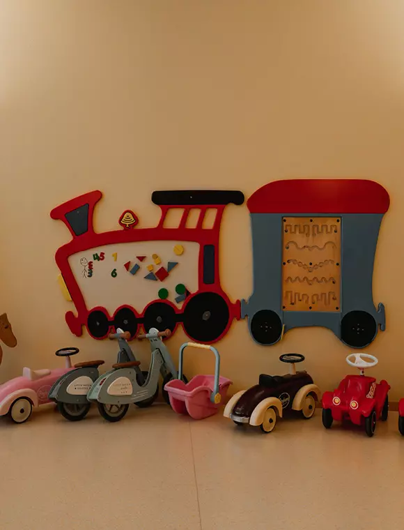 Wand mit Spielzeugzug und Rutschfahrzeugen für Kinder