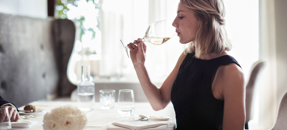 una signora beve del vino bianco da un calice durante il pranzo all'hotel Giardino Marling